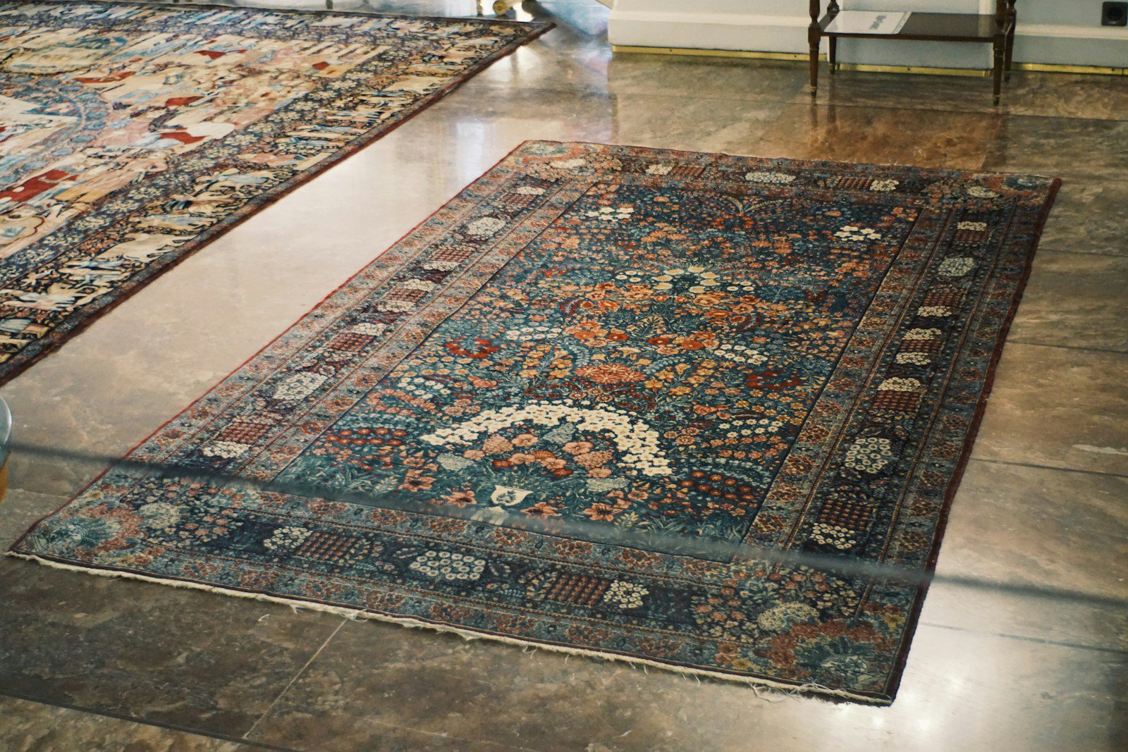 An ornate persian rug displayed on a polished floor.