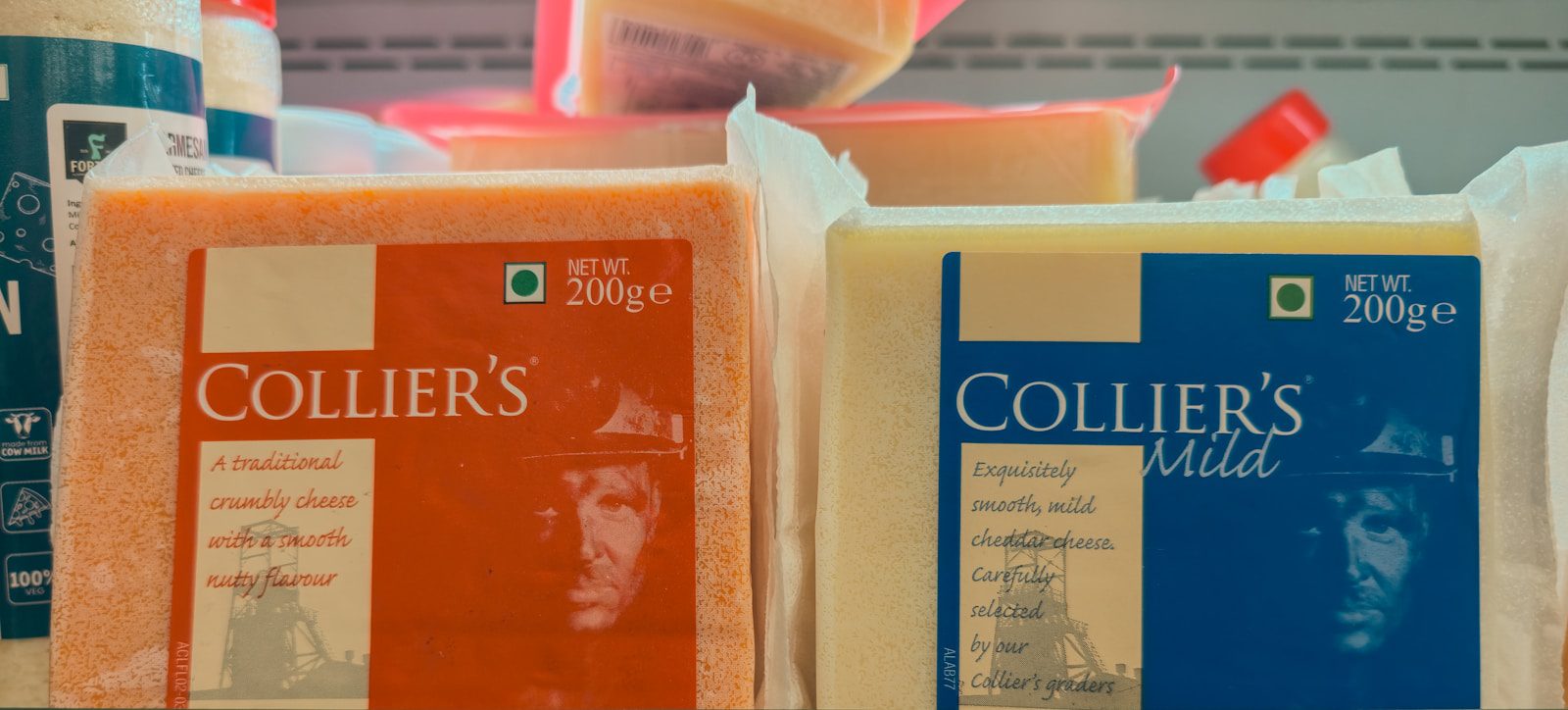 Two blocks of collier's cheese on a shelf.