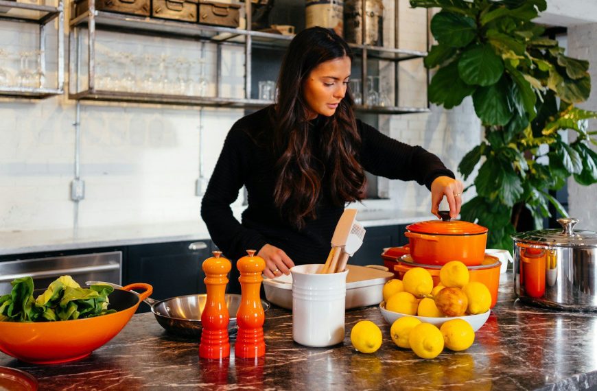 woman standing in front of fruits holding pot's lid