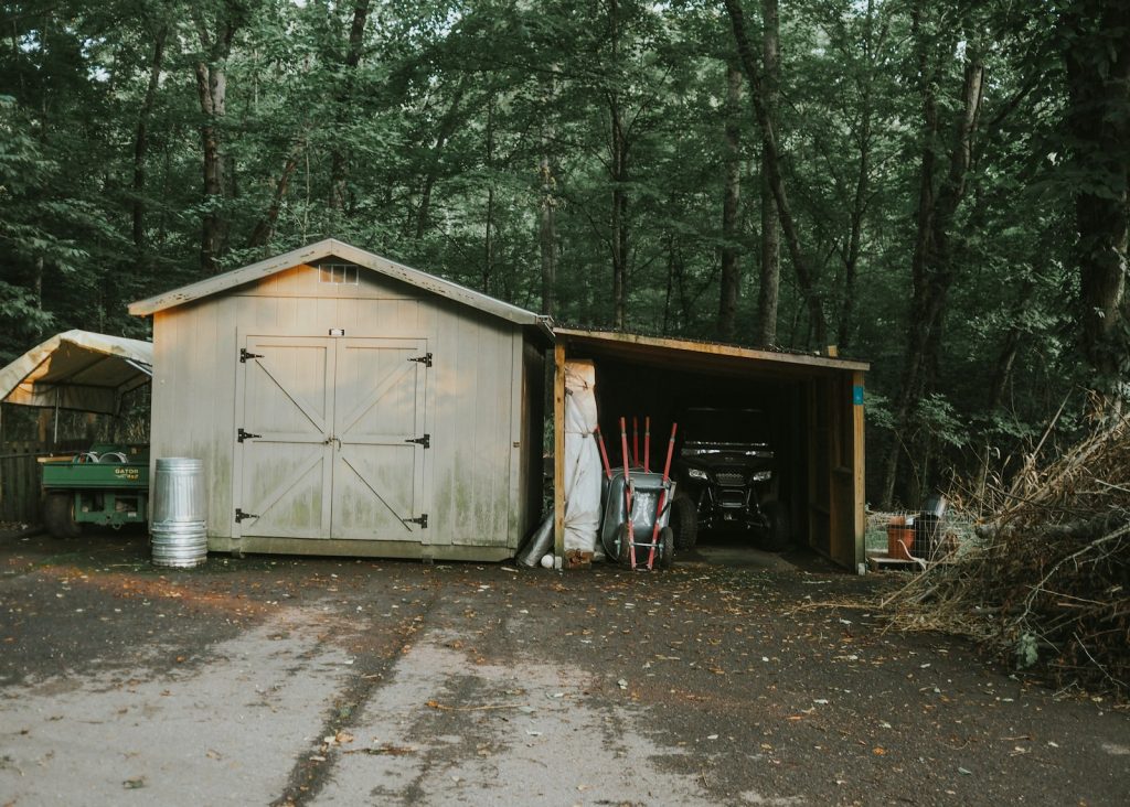 a shed with a door open in the middle of a forest