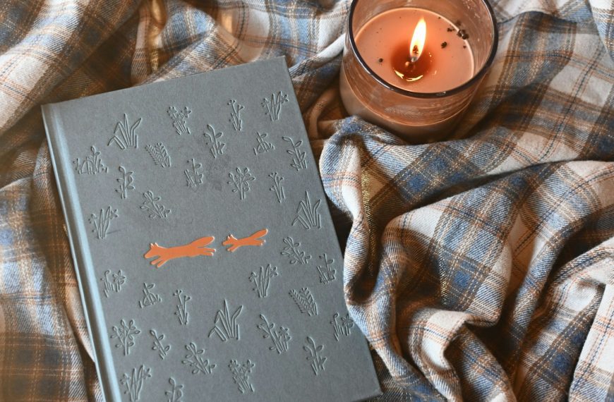 a book sitting on top of a blanket next to a candle