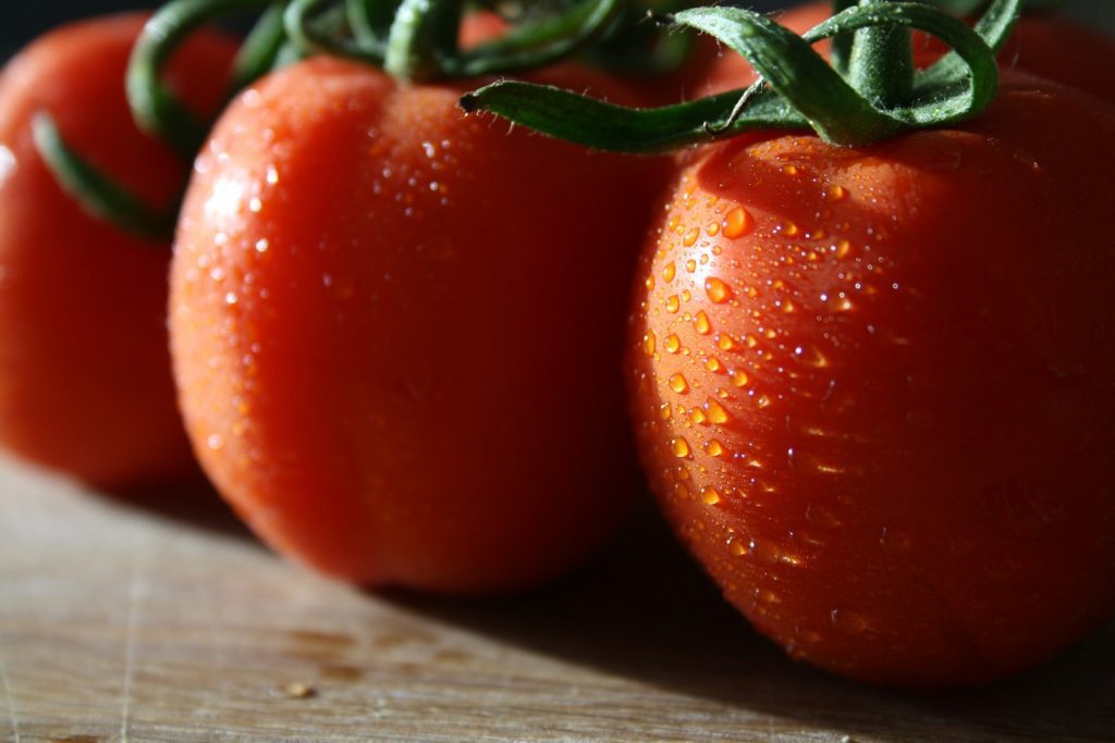 A group of tomatoes sitting on top of a wooden table