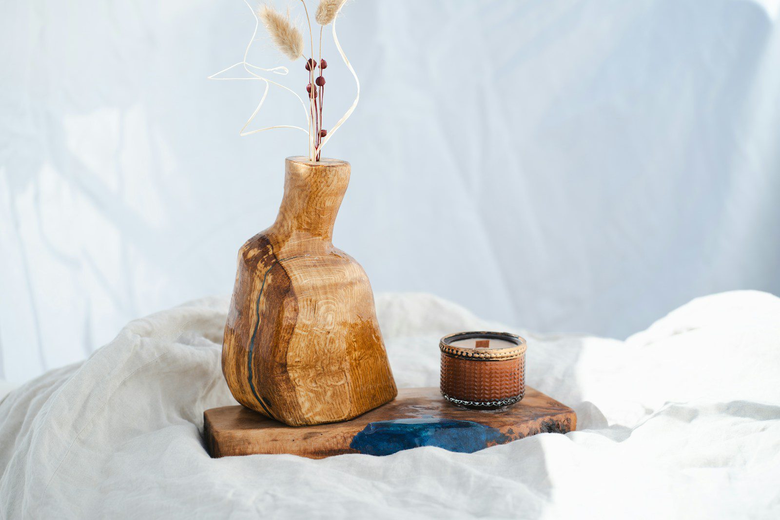 A wooden vase with flowers and a candle.