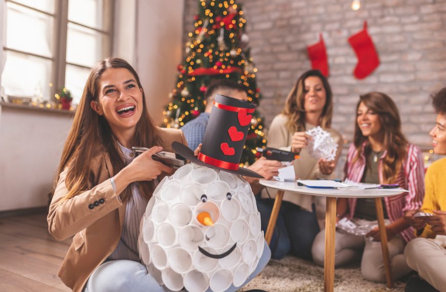 woman smiling while holding Christmas decorations