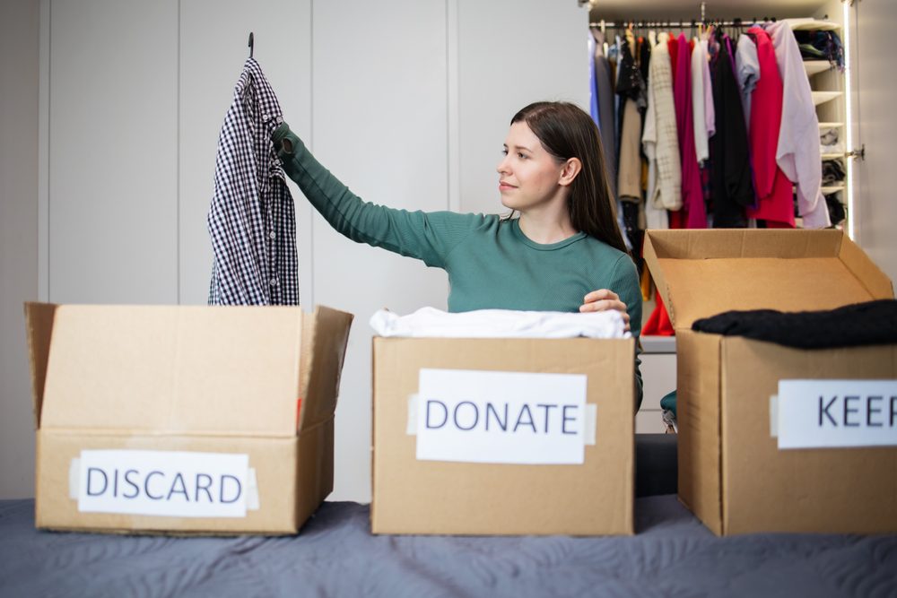 Woman decluttering stuff at home. different cartons to donate,discard and keep