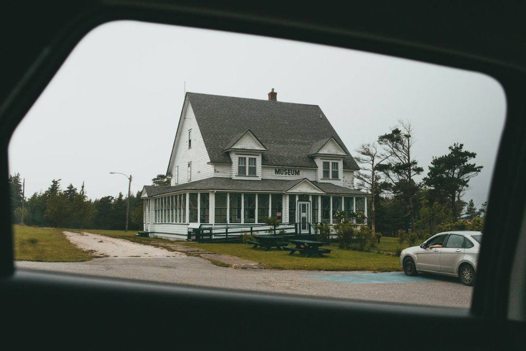 white car parked beside white and gray house