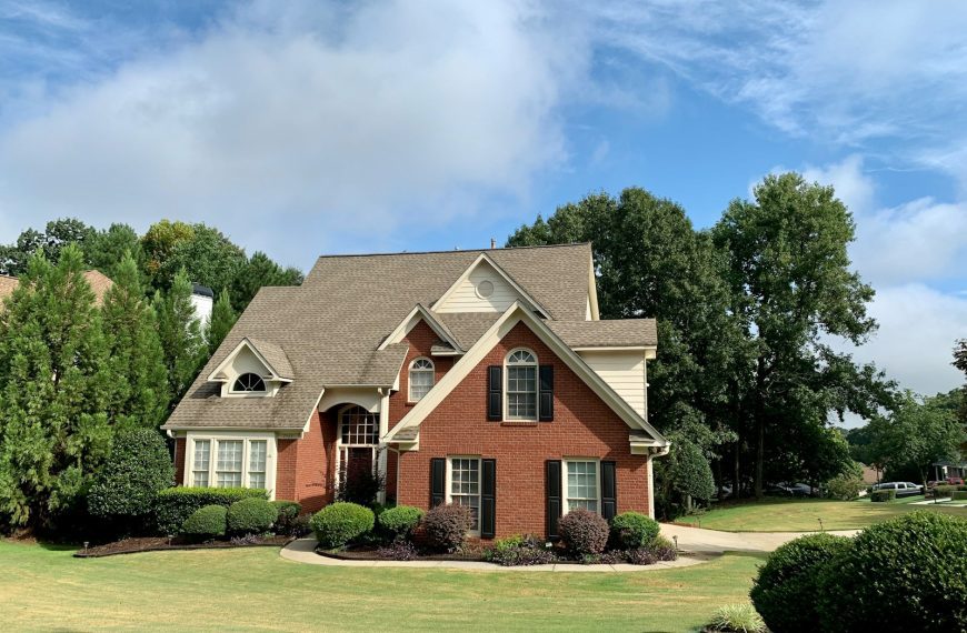 brown and white concrete house near green trees under blue sky during daytime