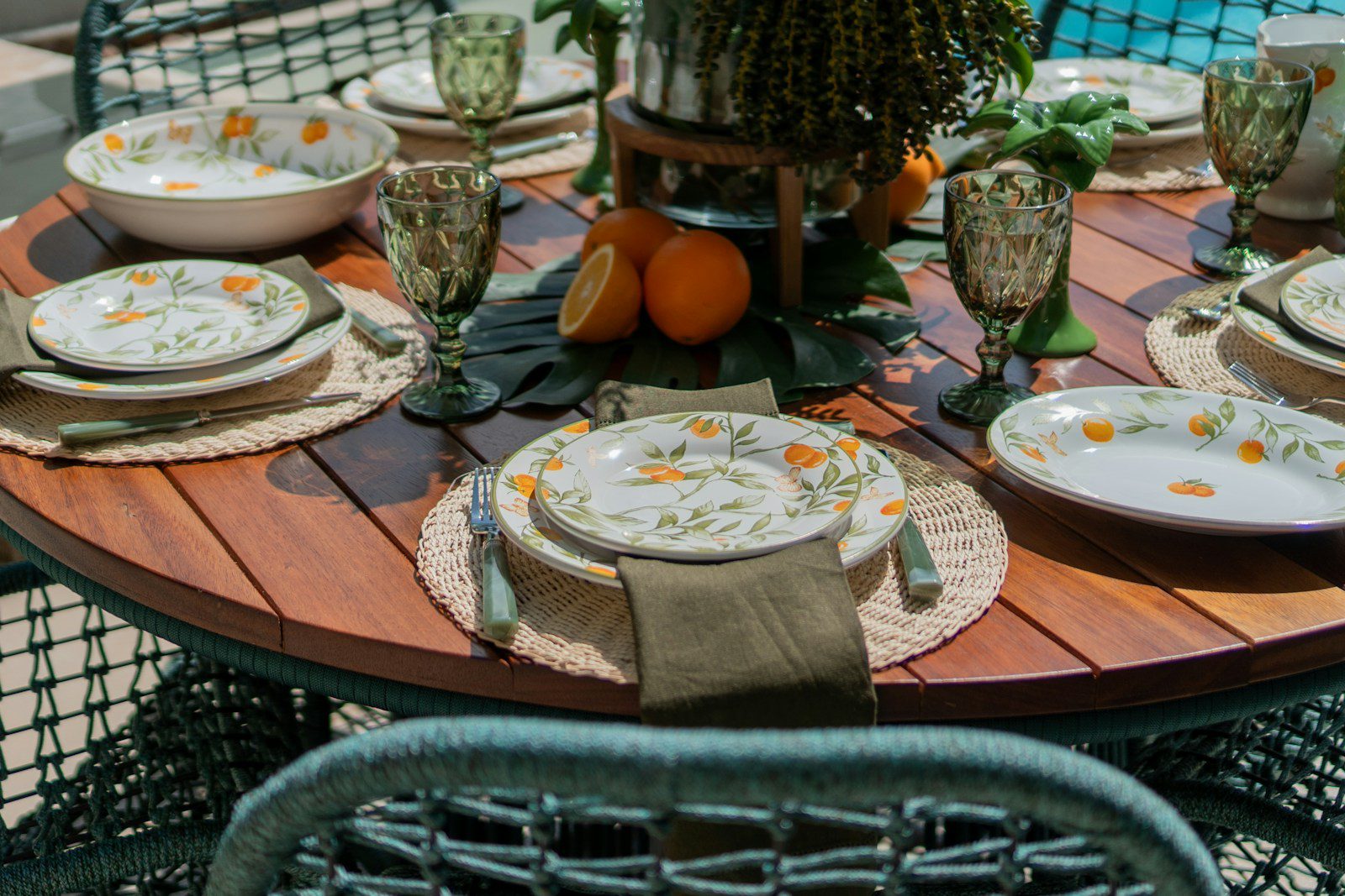 a table set with plates and silverware with a potted plant in the background