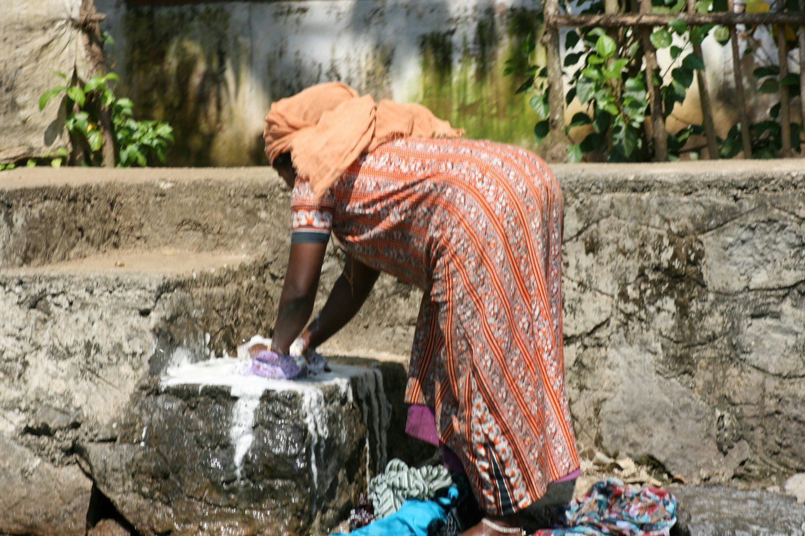 A woman is washing her clothes on the street