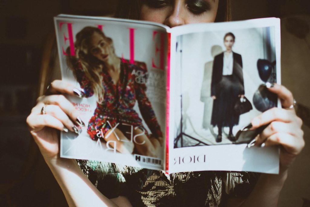 A woman reading a fashion magazine indoors. Ideal for lifestyle and fashion content.