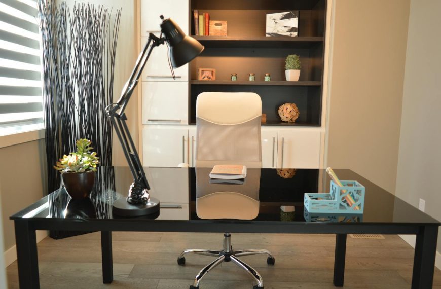 Stylish modern office workspace featuring a black desk, lamp, and white chair with shelving.