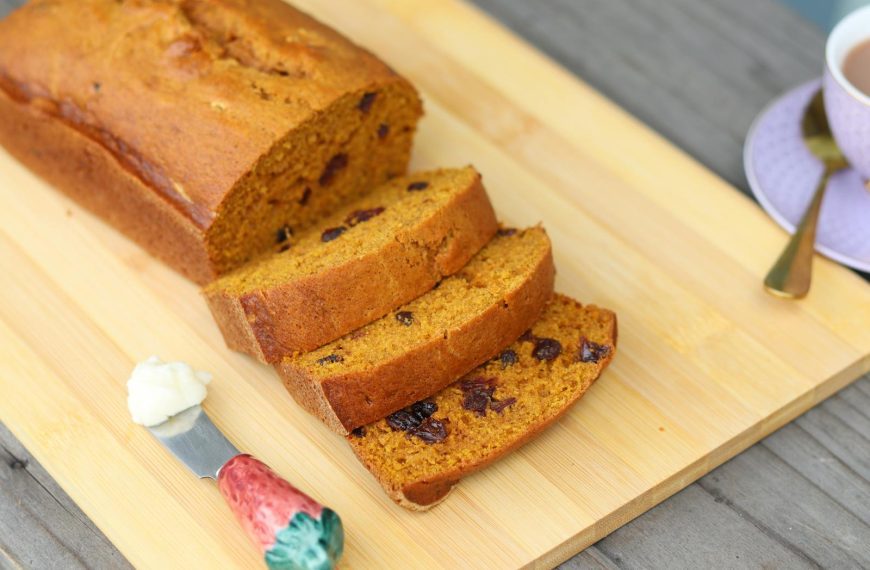 Freshly baked pumpkin bread with raisins on a cutting board, perfect for a cozy meal.