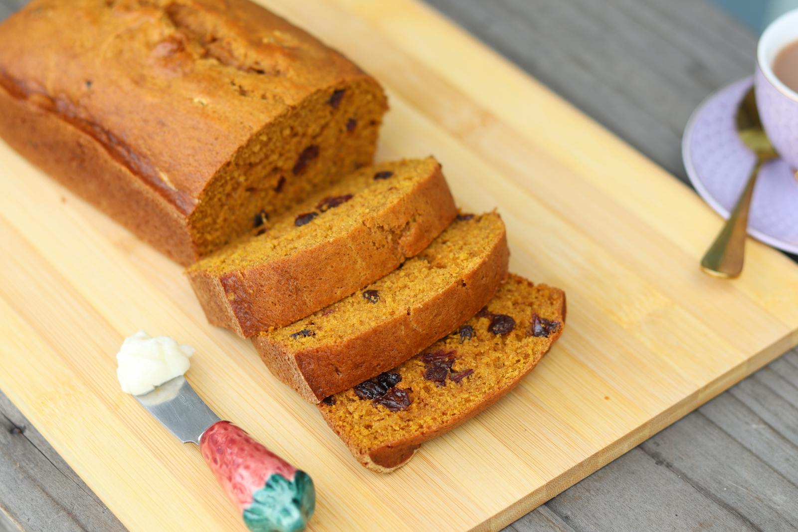 Freshly baked pumpkin bread with raisins on a cutting board, perfect for a cozy meal.