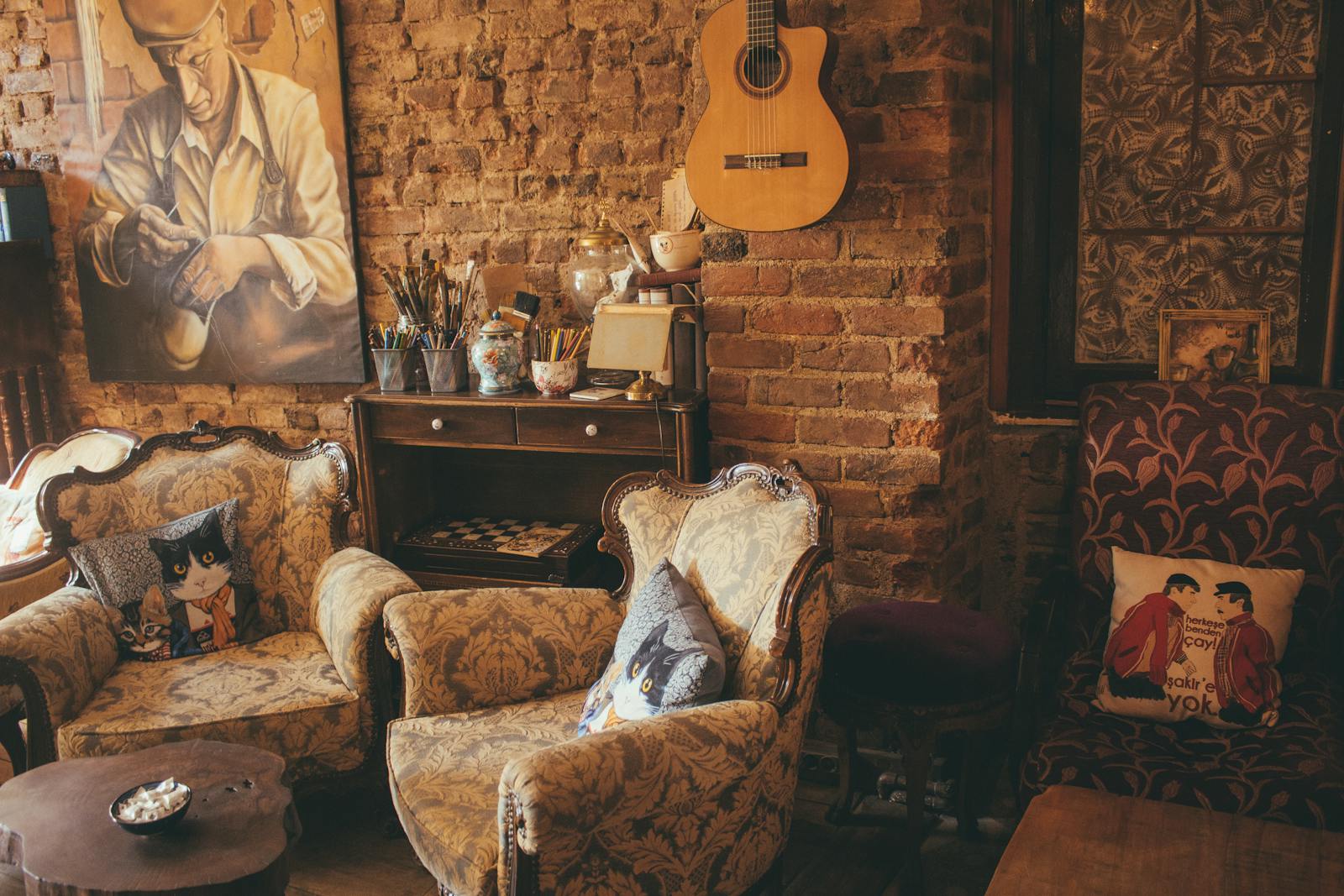 Warm vintage room with armchairs, guitar, and artwork on a brick wall, creating a cozy atmosphere.