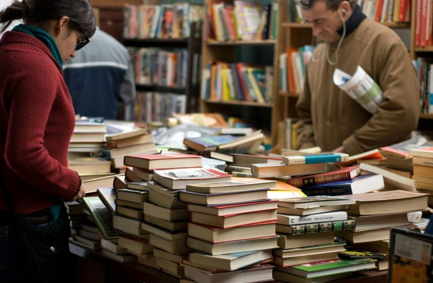 People browsing a large selection of books at a bookstore or market.