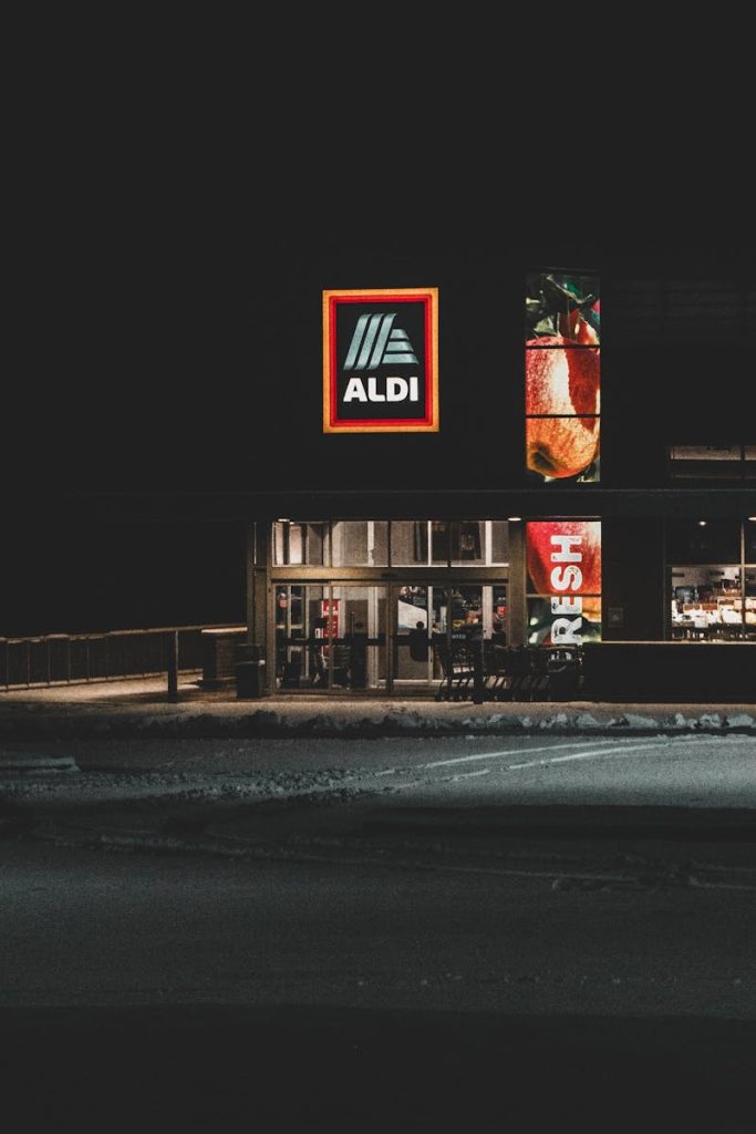 A nighttime winter view of an Aldi storefront with a prominent logo, captured in Roeland Park, KS.