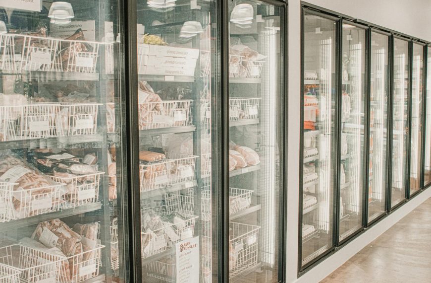 Frozen meats in a retail freezer with transparent doors and organized sections.