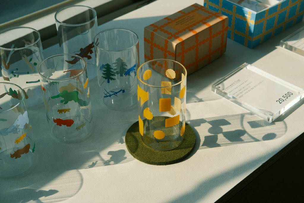 Aesthetic arrangement of patterned glasses and boxes on a sunlit table, casting interesting shadows.