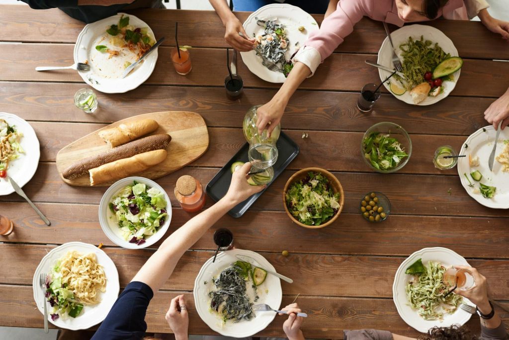 An overhead shot of a dining table featuring various pasta dishes and salads shared by a group.
