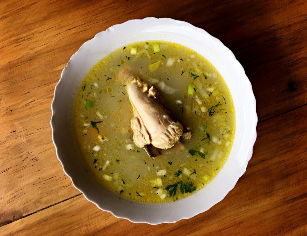 Delicious Ecuadorian chicken soup with vegetables in a white bowl, perfect for a comforting meal.