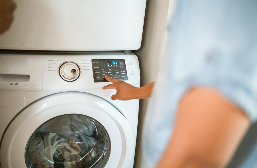 Hand selecting laundry options on a digital washing machine control panel indoors.