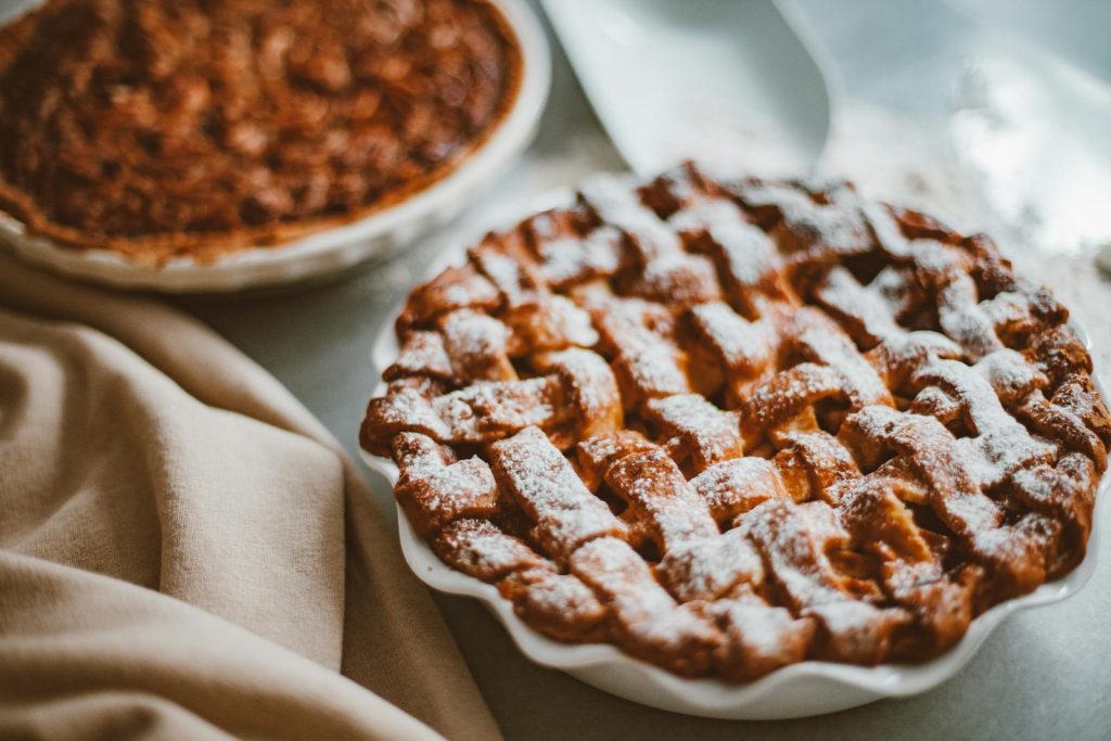 Freshly baked apple pie with lattice crust dusted with icing sugar, perfect for dessert.