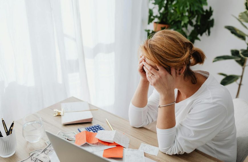 Woman stressed over financial receipts at a desk, dealing with expenses and calculations.
