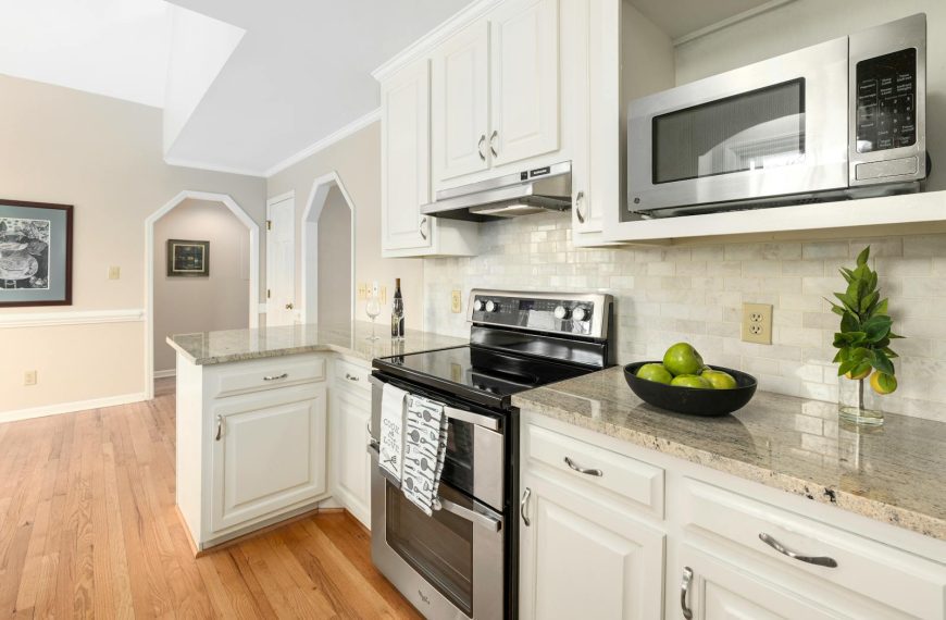 Bright and spacious kitchen featuring white cabinets, granite countertops, and stainless steel appliances.