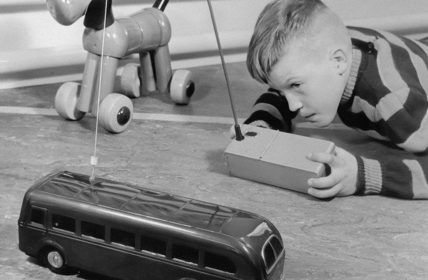 a young boy laying on the floor next to a toy bus