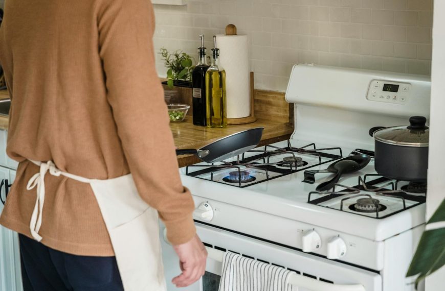 A person preparing food on a gas stove in a cozy kitchen setting.