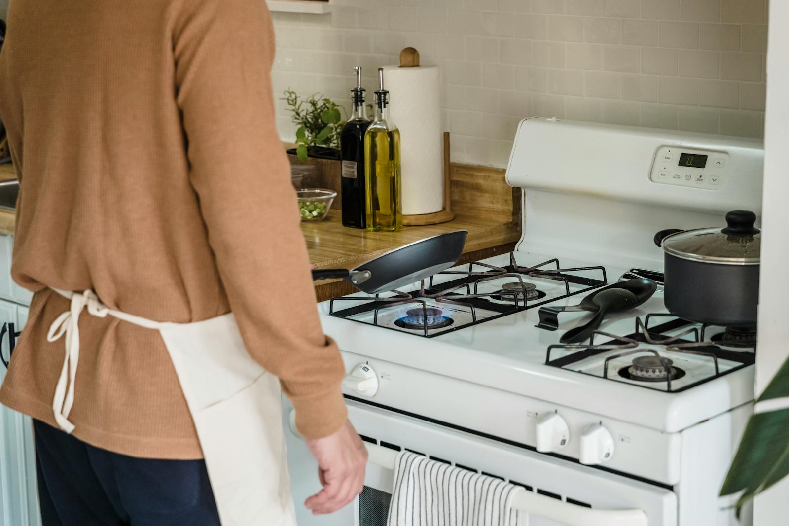A person preparing food on a gas stove in a cozy kitchen setting.