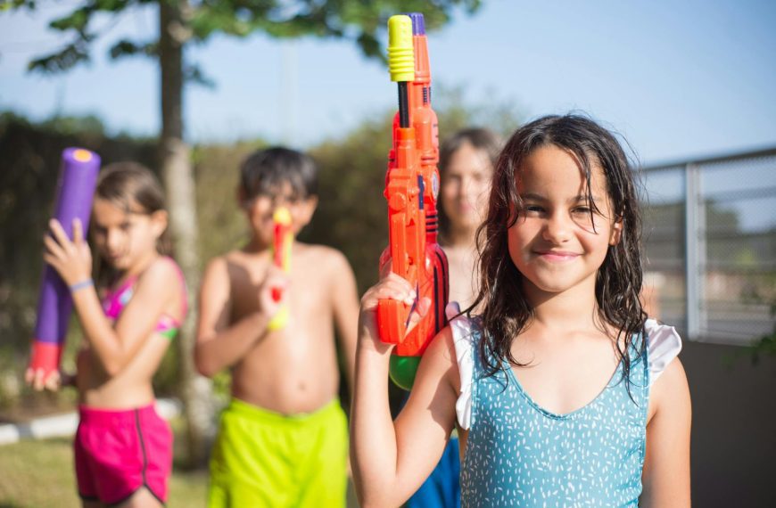 Children enjoying a fun day outdoors with water guns, smiling under the sun.