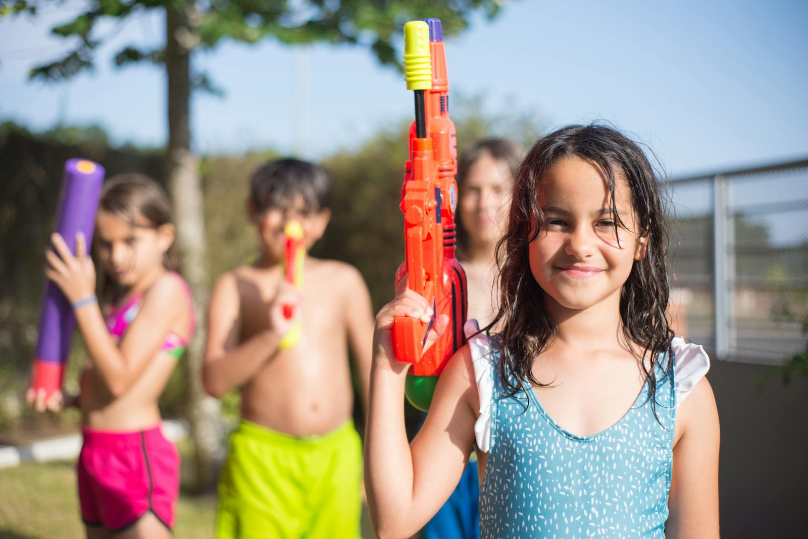 Children enjoying a fun day outdoors with water guns, smiling under the sun.