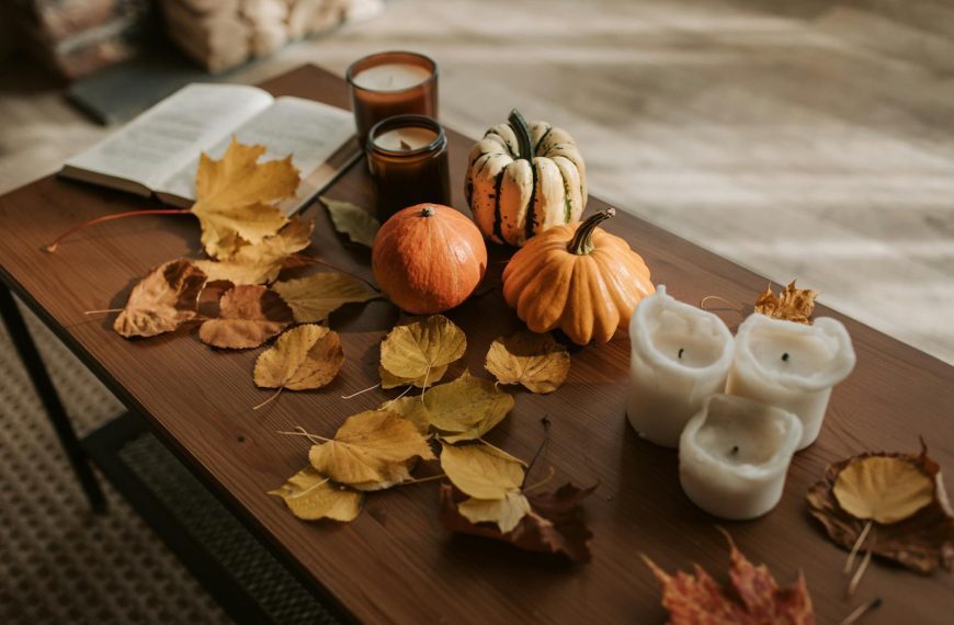 Warm autumn setting with pumpkins, candles, and leaves creating a cozy fall atmosphere.