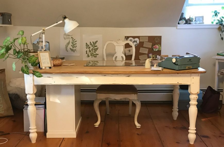 a room with a desk, chair, lamp and pictures on the wall