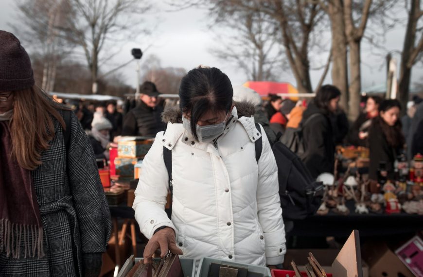 man in white jacket standing near brown wooden table