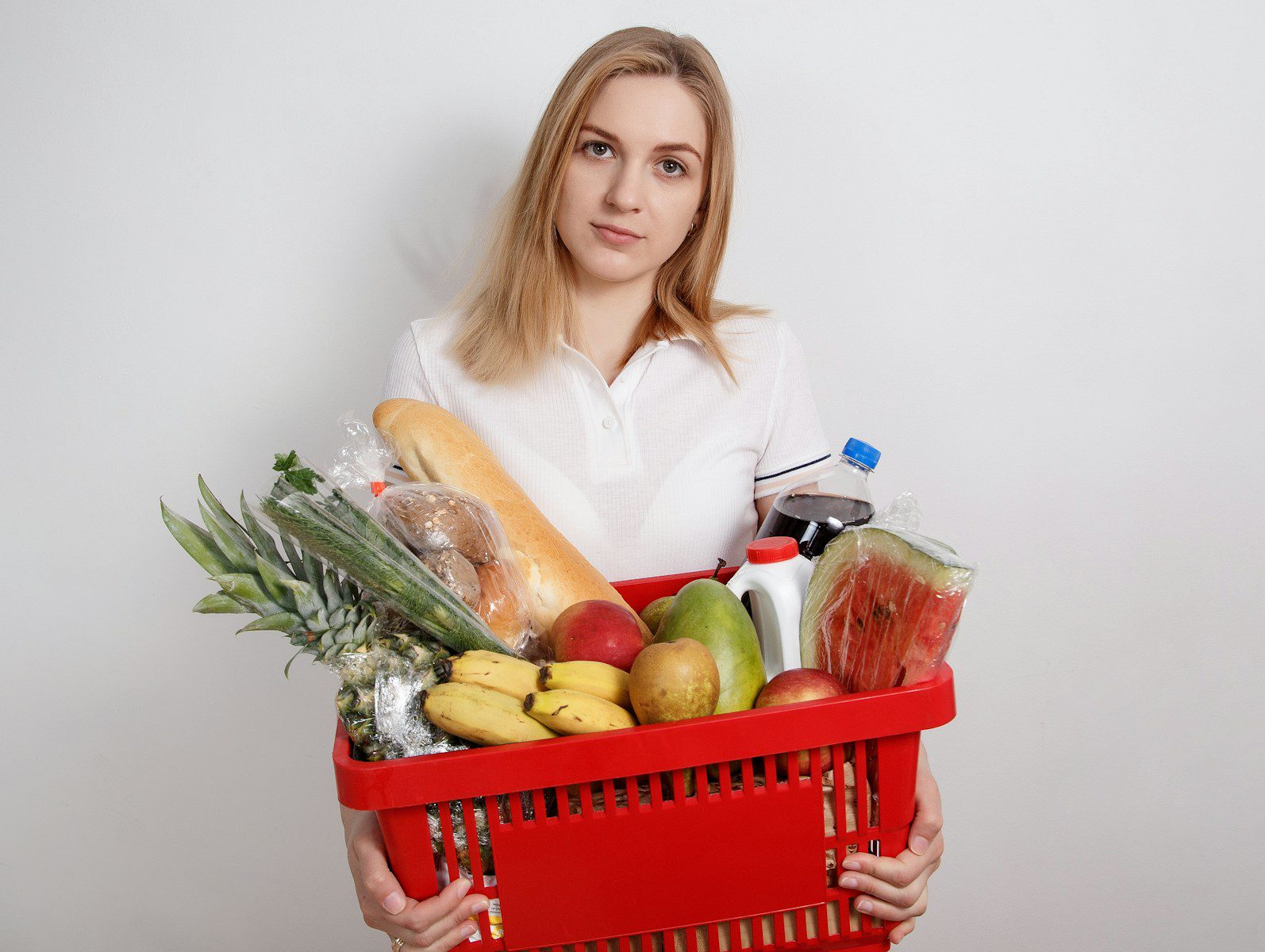 woman in white long sleeve shirt holding red plastic basket with fruits