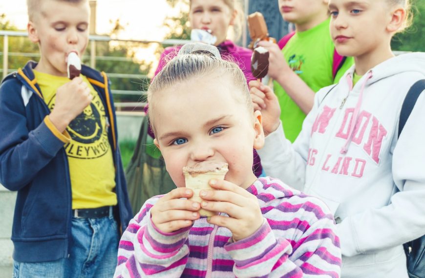 boy in white and pink striped long sleeve shirt holding ice cream