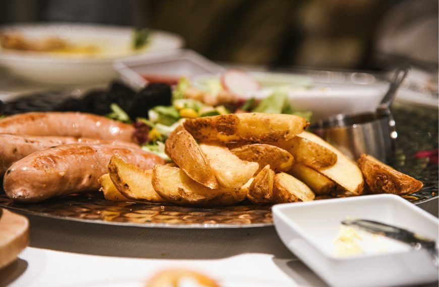 a plate of food with sausages, potatoes and salad