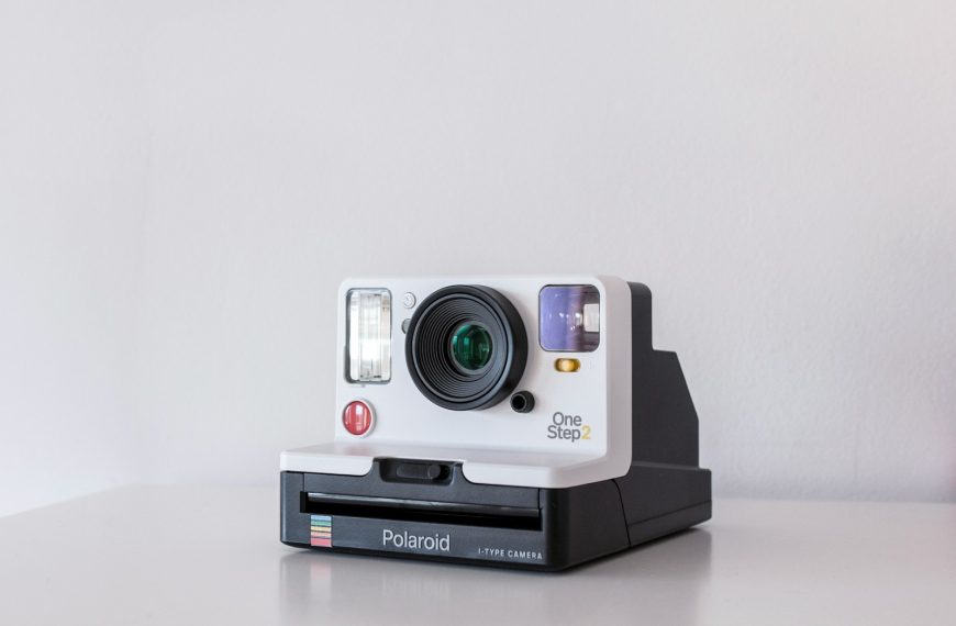 white and black Polaroid One Step 2 instant camera on white board
