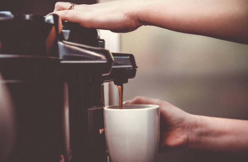 person using coffeemaker with white ceramic mug