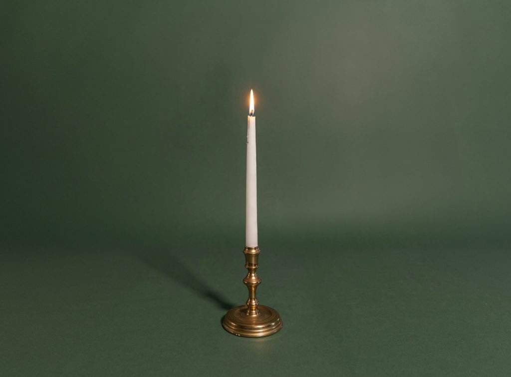A single white candle sitting on top of a table
