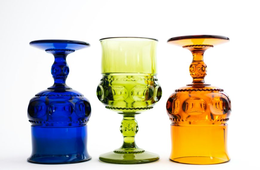 three different colored glass vases sitting next to each other