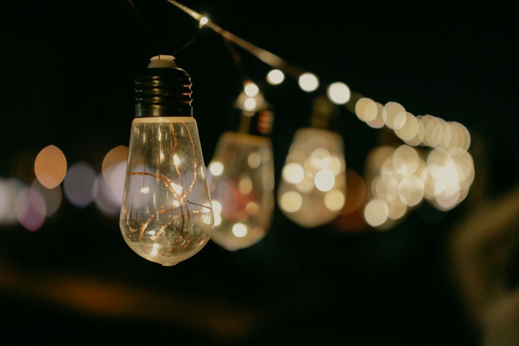 Close-up of glowing string light bulbs creating a warm bokeh effect in a dark setting.
