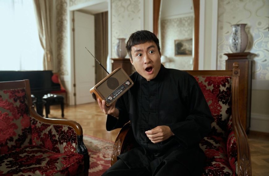 Man in vintage interior expressing surprise while holding a retro radio.
