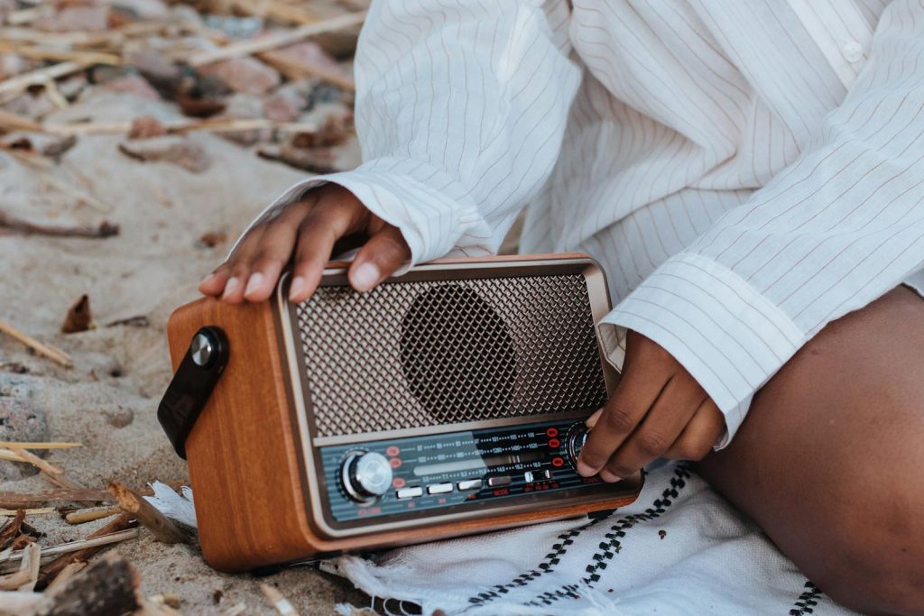 Close-up of hands on a vintage radio at a beach picnic, evoking a nostalgic summer vibe.