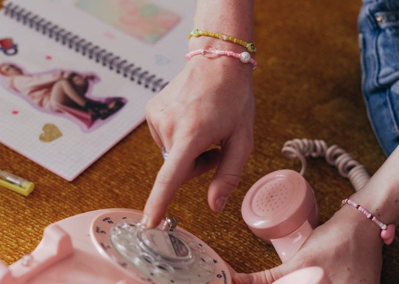 Retro-themed image featuring a pink rotary phone being dialed, evoking 90s nostalgia.