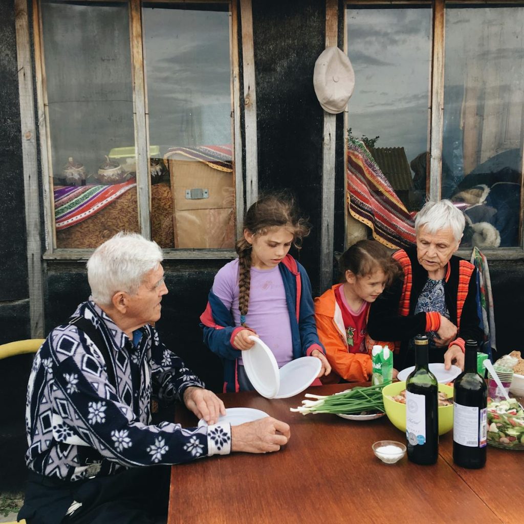 Elderly couple enjoying outdoor dinner with grandchildren, sharing moments and stories together.
