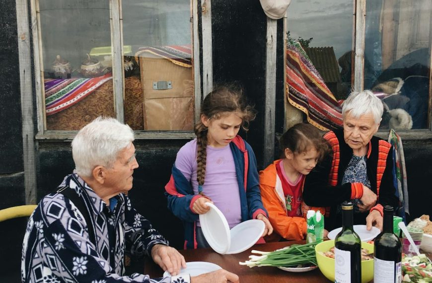 Elderly couple enjoying outdoor dinner with grandchildren, sharing moments and stories together.