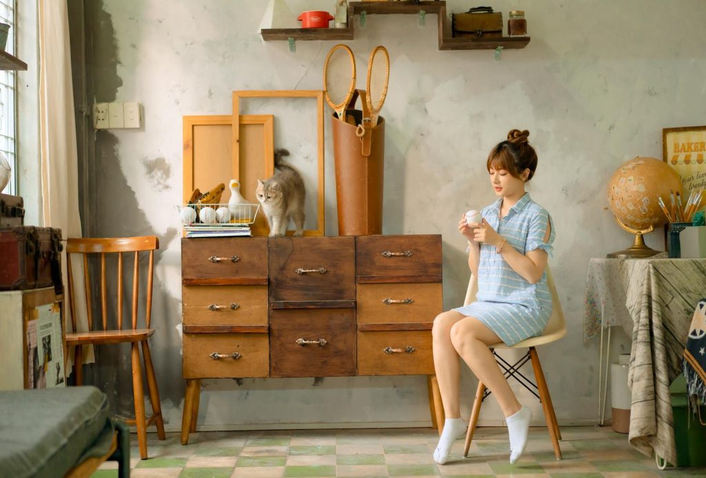 A woman sits in a vintage room with a cat, showcasing cozy interior decor.